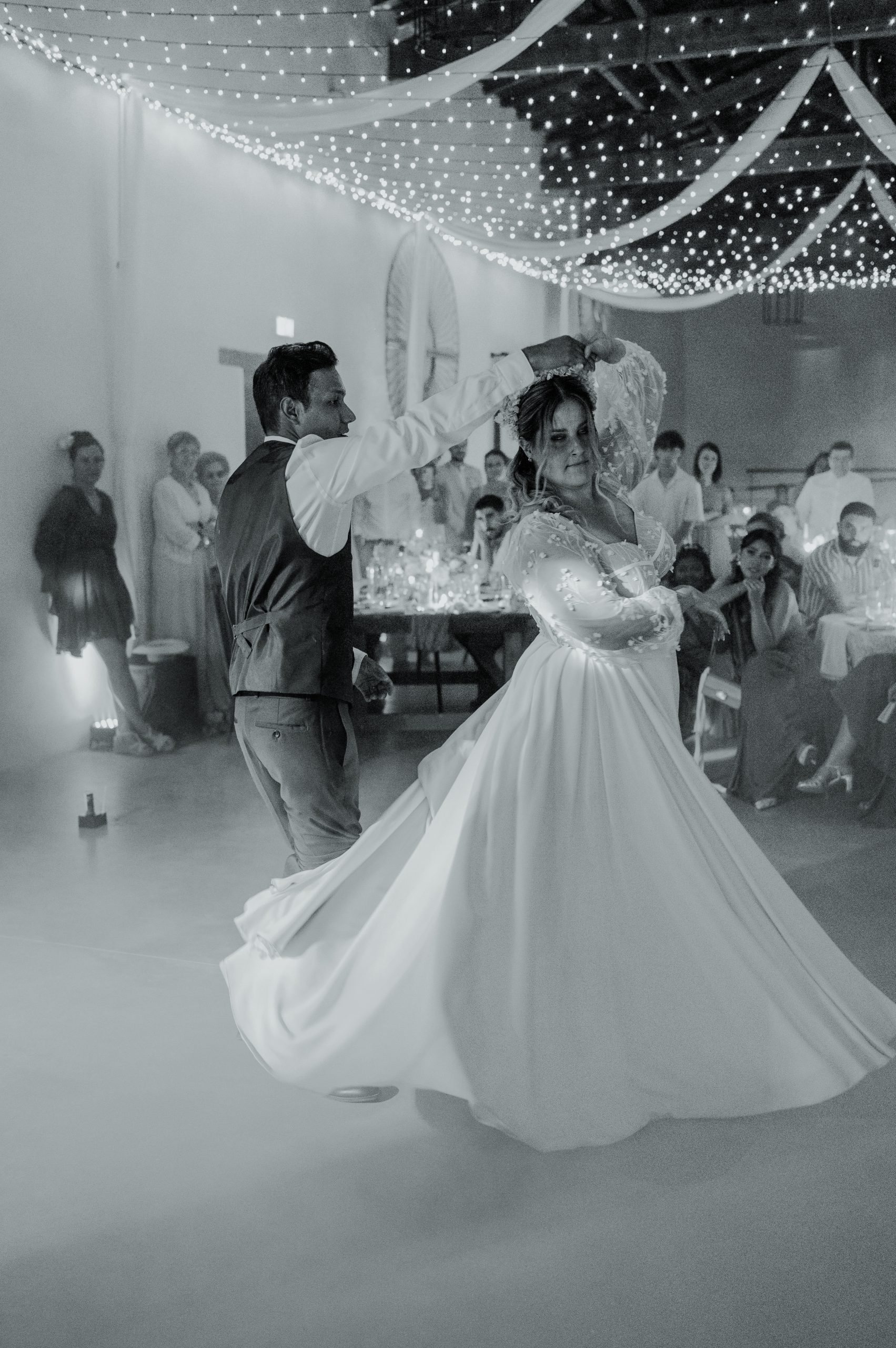 Emma danse avec Maël lors de leur mariage. Sa robe de mariée sur mesure tournoie autour d'elle, dévoilant le volume et la fluidité de sa jupe.