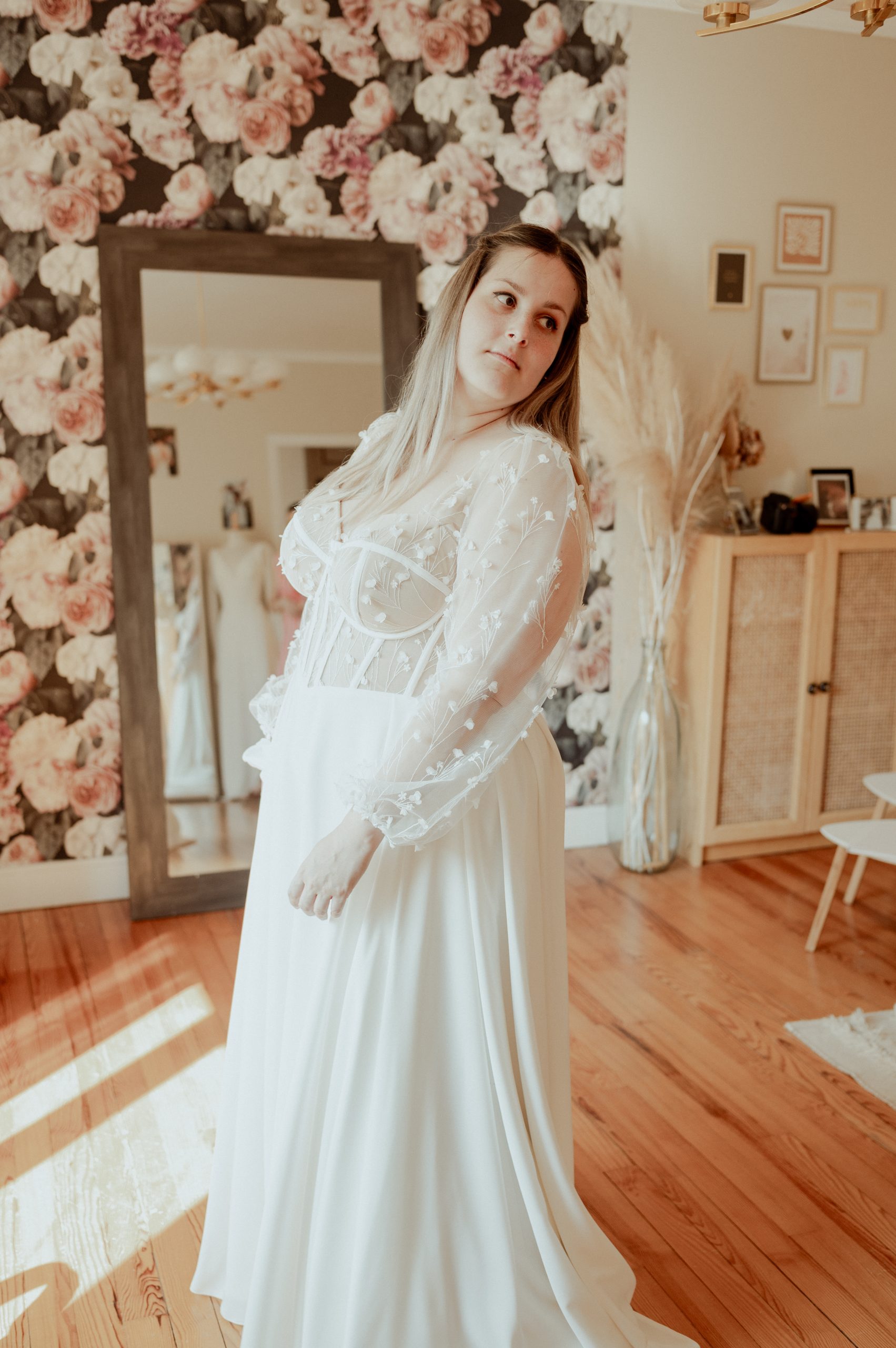 Emma porte sa robe de mariée sur mesure lors du dernier essayage à Toulouse, avec un corset ajusté, des manches en tulle brodé et une jupe fluide.